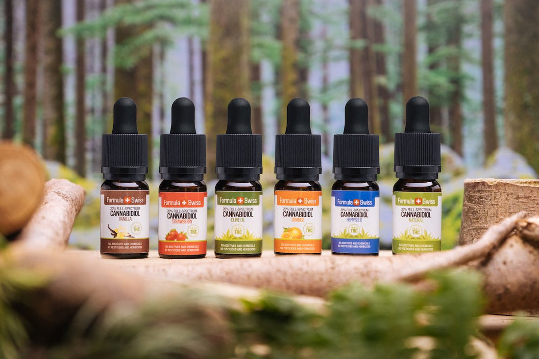 Six Formula Swiss full-spectrum CBD oils in different carrier oils and flavours, in front of a forest