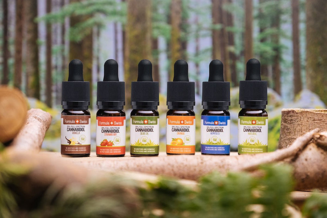Six Formula Swiss full-spectrum CBD oils in different carrier oils and flavours, in front of a forest