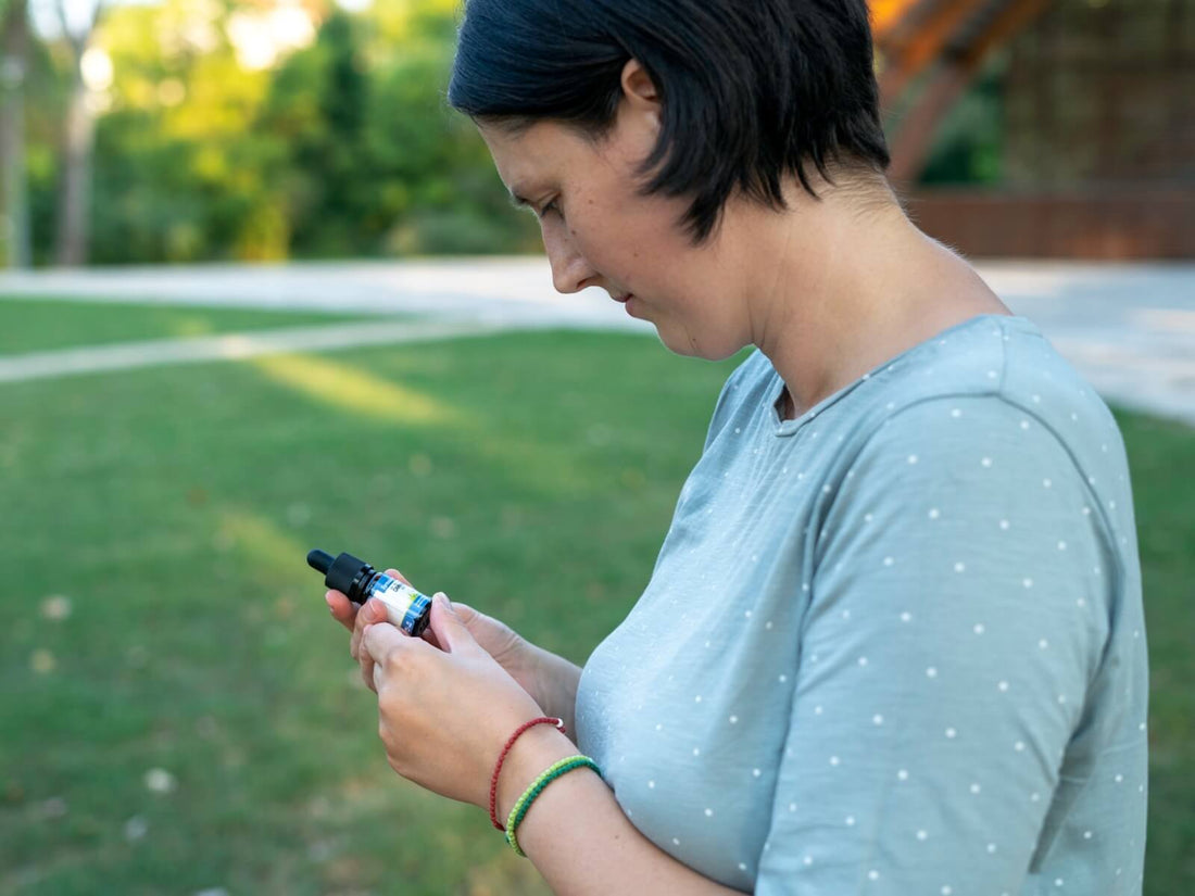 Woman looking at a Formula Swiss CBD oil bottle in her hand outdoors