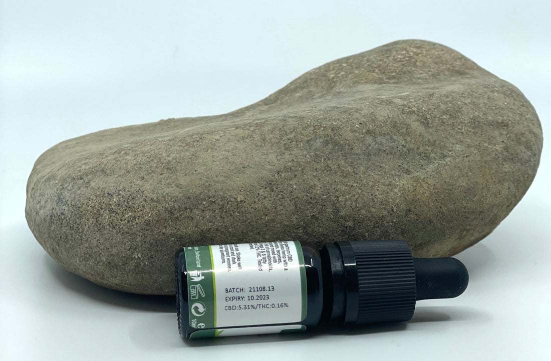 10 ml Formula Swiss full-spectrum CBD oil against a stone, its batch label showing CBD 5.31% and THC 0.16%